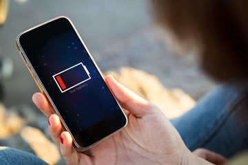 woman sitting in the street holding her smartphone with low batt