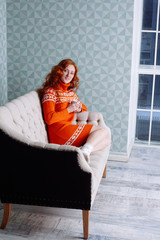 Cozy portrait of  woman in warm sweater on the bed with cup of t