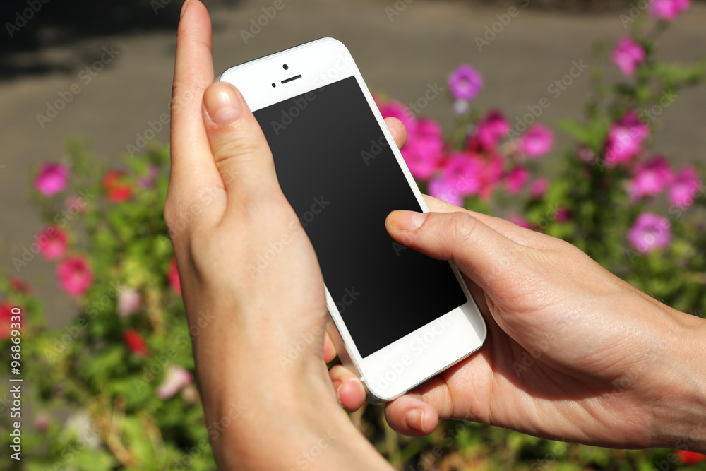 Female hands holding smart mobile phone outdoors