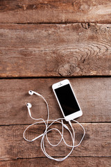 Poster - White cellphone with headphones on wooden background