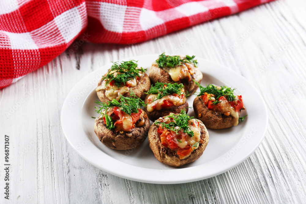 A plate with stuffed mushrooms on wooden background
