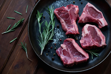 Wall Mural - Raw T-bone lamb steaks with seasonings in a frying pan, close-up