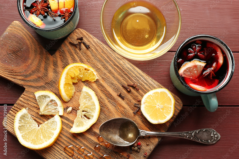 Mulled wine in a mug with citruses on wooden background, close up