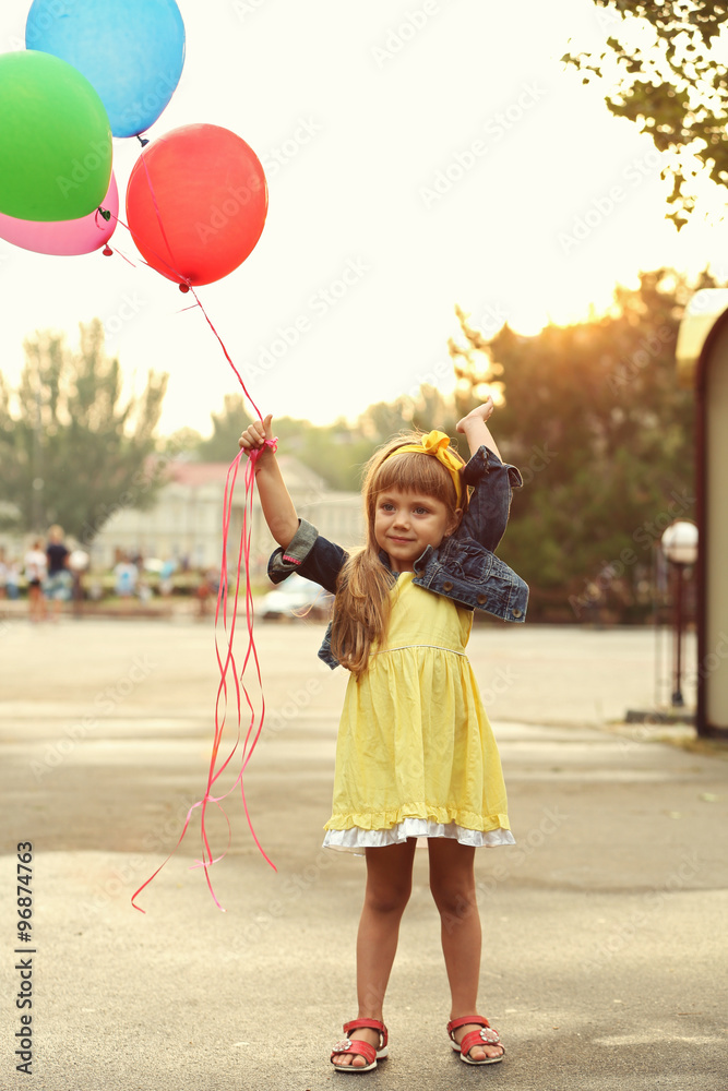 Little girl with balloons outside