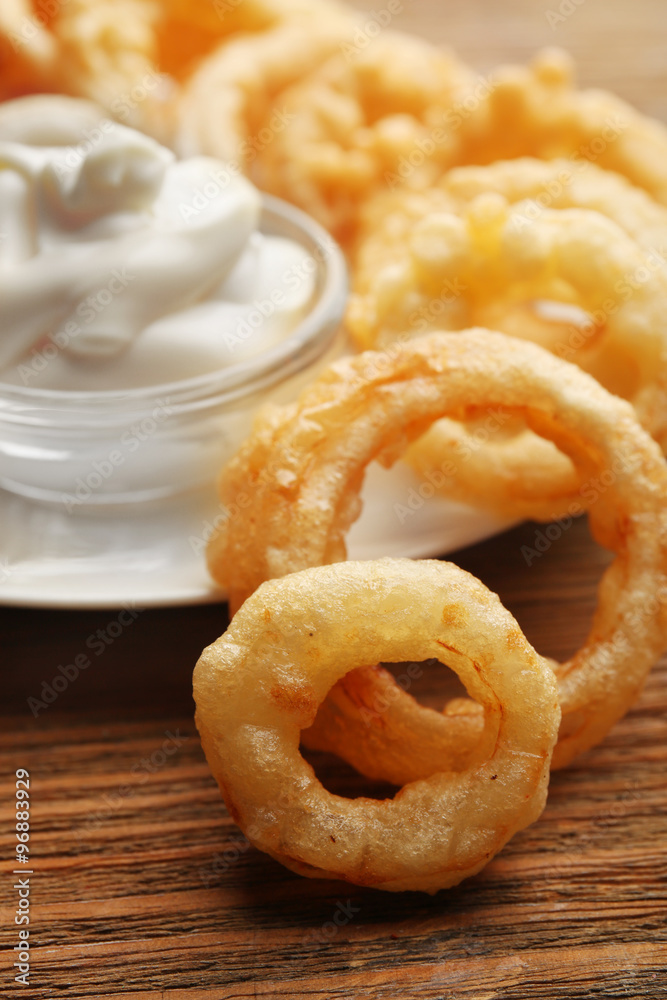 Chips rings with white sauce on plate on wooden background