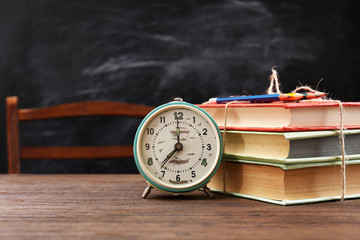 Poster - Colourful pile of books with clock on wooden table