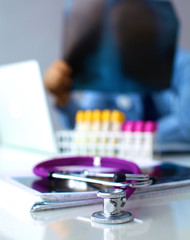 A medical stethoscope near a laptop on table, on white