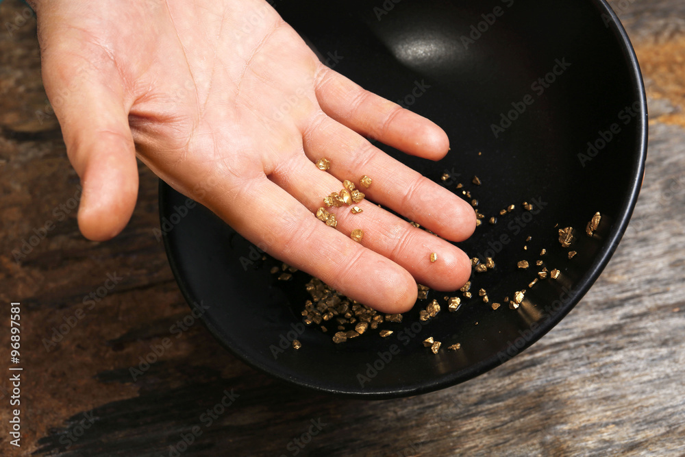 A hand holding gold nugget grains, close-up