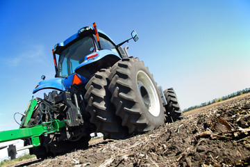 Fototapete - Farmer on a tractor plowed field