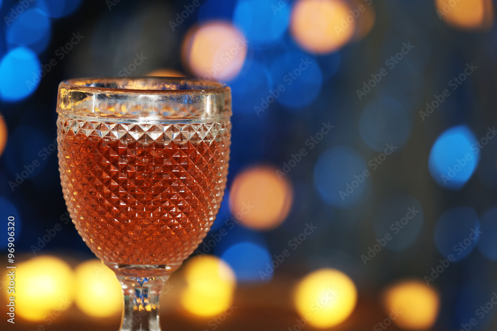 A glass of pink wine on blurred lighted background
