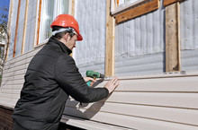 A Worker Installs Panels Beige Siding On The Facade