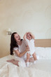 © natalialeb - baby kid with mom playing on a bed under a blanket,