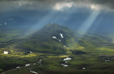 Wall Mural - Sun breaking through the clouds on a mountain on the Laugavegur hiking trail on Iceland.