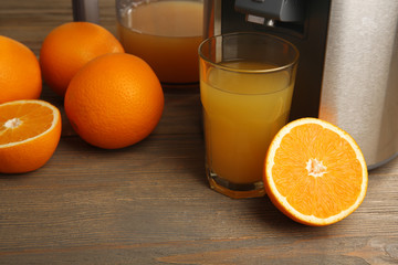 Poster - Stainless juice extractor with glass of orange juice on wooden background, close up