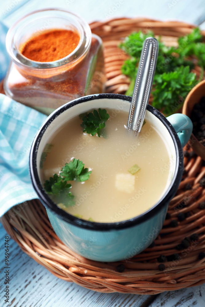 Mug of soup on wicker mat on a table