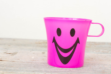 Smiling, Plastic glass of various color on wooden background