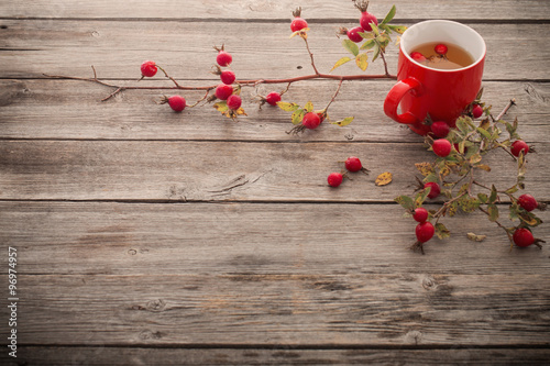 Fototapeta na wymiar cup of tea with hip roses, on wooden table