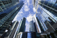 Modern Business Office Skyscrapers, Looking Up At High-rise Buildings In Commercial District, Architecture Raising To The Blue Sky With White Clouds, Bottom View 