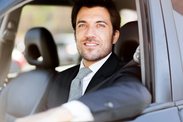 Portrait of an handsome smiling business man driving his car