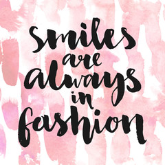 Wall Mural - Smiles are always in fashion. Inspirational quote handwritten with black ink and brush, custom lettering for posters, t-shirts and cards. Vector calligraphy on pink watercolor strokes background