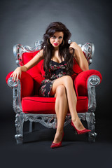 Wall Mural - Young woman in a red chair. Retro style.