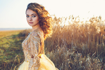 Cute lady walking through the field. Sunset background