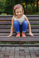 little cute girl sits on bench