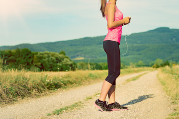 Wall Mural - Attractive female runner holding headphones, ready for her workout