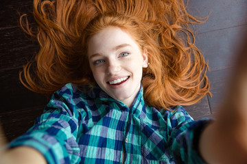 Sticker - Cheerful redhead woman making self image lying on the floor