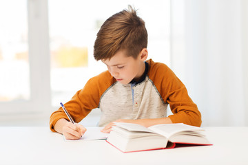 Wall Mural - student boy with book writing to notebook at home