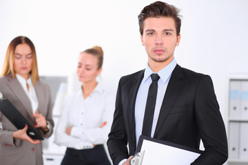 Cheerful business man in office with colleagues in the background, sturt  up team