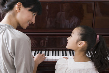 mother and daughter playing the piano