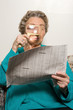 Woman reading newspaper with magnifying glass