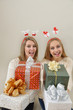 two smiling young women offer gifts