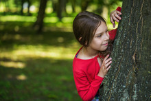 Little Smiling Girl Hiding Behind Tree