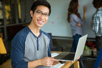 Sticker - Happy asian man holding laptop and studying with friends