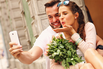 Wall Mural - Young romantic couple taking selfie in the city