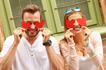 Sticker - Young romantic couple covering eyes with hearts in the city