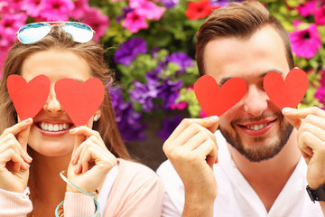 Wall Mural - Young romantic couple covering eyes with hearts