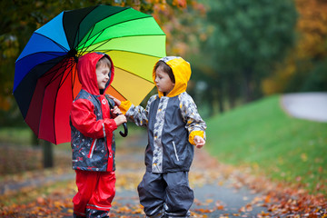 Sticker - Two adorable children, boy brothers, playing in park with umbrel