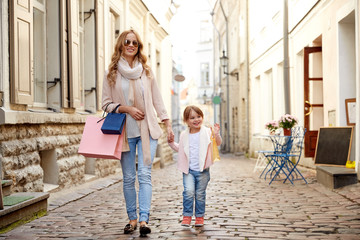 Wall Mural - happy mother and child with shopping bags in city