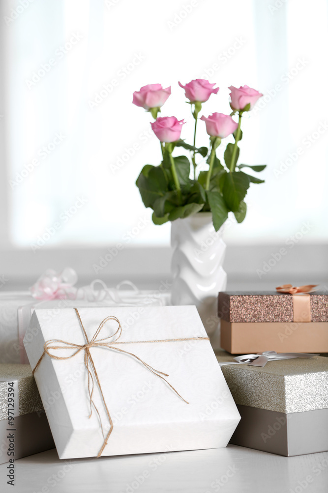 Composition of cute gift boxes and roses on white table