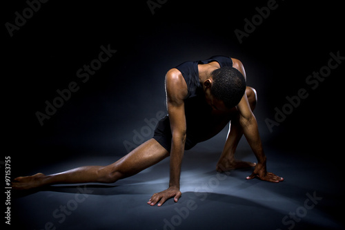 Fotografie, Obraz Black male dancer practicing warm up exercises for flexibility
