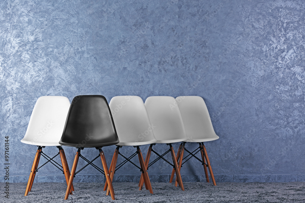 Stylish conception with white and black chairs on grey background
