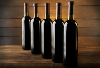 Wall Mural - Wine bottles in a row on the table against wooden background