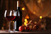 Red Wine And Christmas Ornaments On Wooden Table On Golden Background