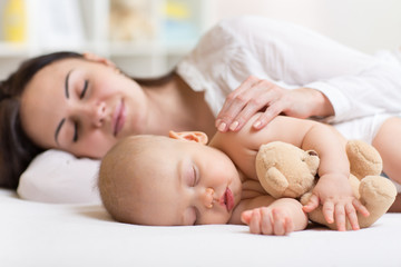 mother and baby sleeping together in a bedroom