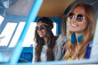 smiling young hippie women driving minivan car