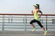 © lzf - young fitness woman runner running at seaside