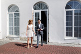 Fototapeta Na drzwi - Elegant blonde bride and groom in expensice grey suit walking ou